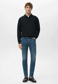 Musta pitkähihaisen poolopaita, slim fit -siniset farkut ja mustat loafers-kengät. Rentoon tyyliin kuuluvat poolopaidan kaulus ja napit.