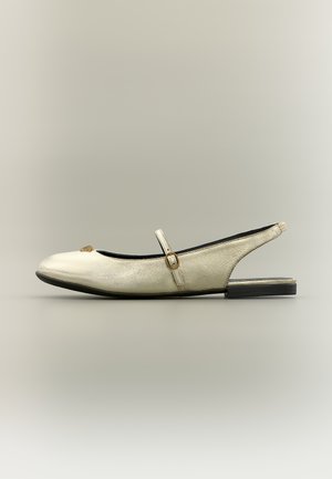 Off-white leather slingback flat with a thin strap and small gold buckle across the instep, and a low black sole.