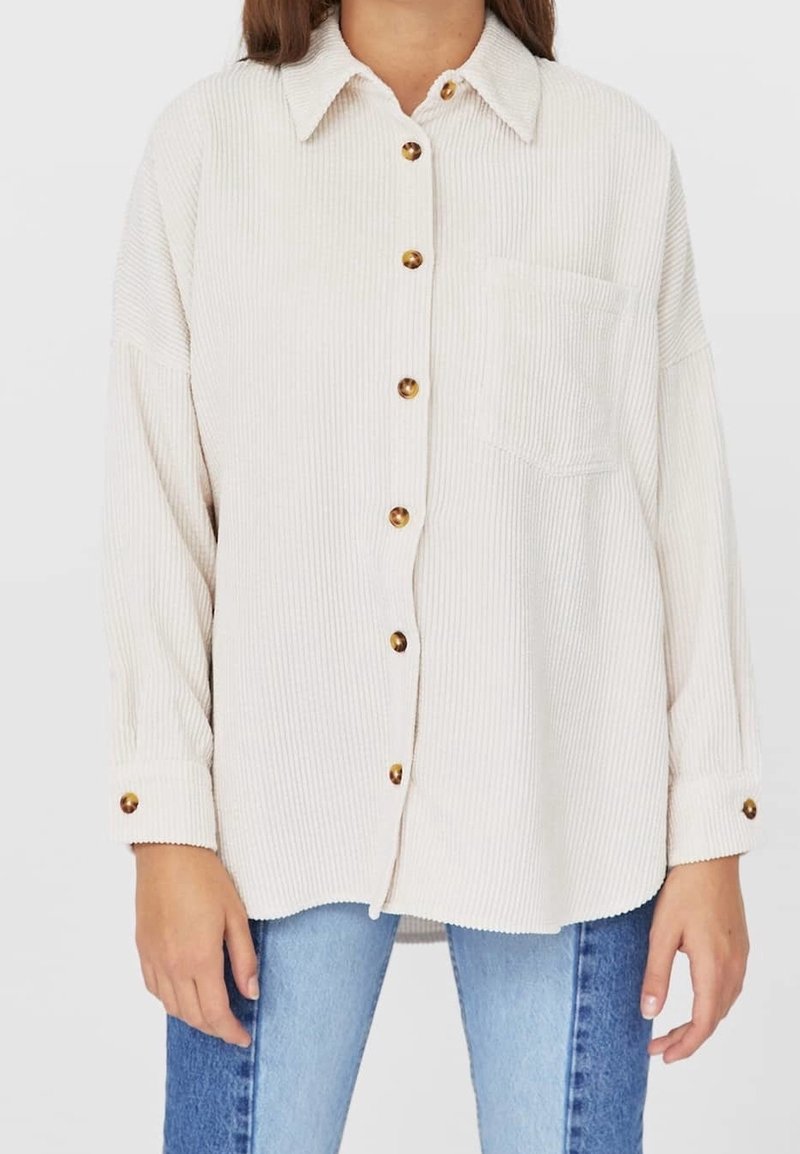 Beige corduroy shirt with a button-down front, large golden buttons, a chest pocket, and long sleeves with button cuffs.