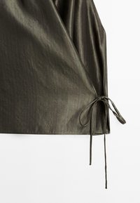 Olive green wrap top made from smooth fabric, featuring a textured pattern, elongated sleeves, and a tied side fastening.