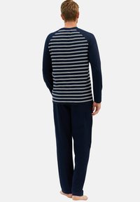 Ensemble de pyjama bleu marine comprenant un haut à manches longues rayé et un pantalon assorti uni. Matière douce, coupe décontractée et design casual.