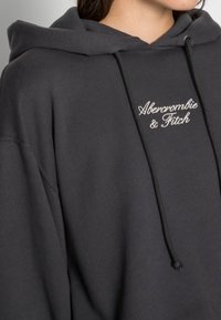 Felpa nera con cappuccio caratterizzata da una vestibilità ampia. Presenta un cordino regolabile, polsini a coste e il logo ricamato "Abercrombie & Fitch".
