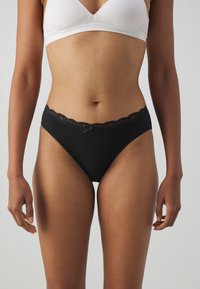 Black panties featuring a lace trim at the waistband, a smooth fabric texture, and a design with a small bow accent.