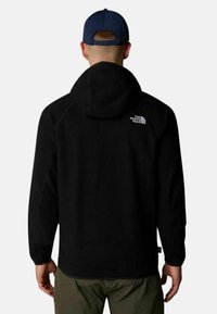 Felpa nera con grande cappuccio e maniche raglan. Il retro presenta un logo bianco nell'angolo superiore sinistro. Tessuto morbido.