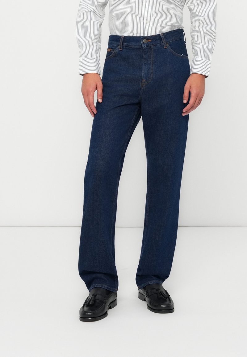 Jeans en denim rectos de color azul oscuro, con cierre frontal, cinco bolsillos y detalles en costura de contraste.