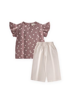 Kinderoutfit mit einem fliederfarbenen kurzärmligen Oberteil mit weißem Blumenmuster und hellbeigen weiten Hosen mit elastischem Bund.
