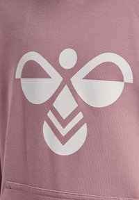 Motif géométrique abstrait d'abeille blanche imprimé sur le devant d'un vêtement en tissu mauve.