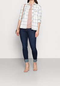 Hvid ternet skjorte med marineblå linjer, parret med en tekstureret pink top, mørke skinny jeans og nude hæle sandaler.