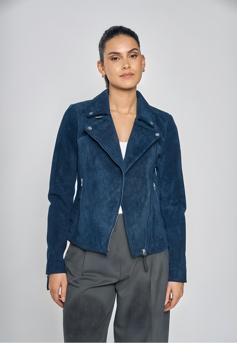 Marineblauwe motorjas van suède met een reverskraag, asymmetrische ritssluiting aan de voorkant en twee zijzakken met rits. Getailleerd silhouet met lange mouwen.