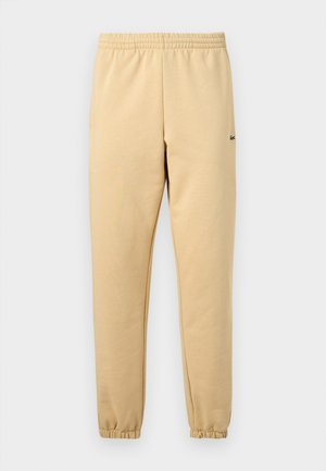 Beige jogger pants with elastic waistband and cuffs, featuring a small embroidered green crocodile logo on the right thigh.