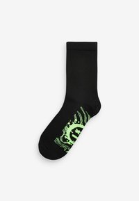 Chaussette en coton noire avec un design graphique néon vert contrastant, présentant des motifs circulaires et ondulés sur le bas.