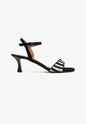 Czarna sandałki na obcasie typu kitten heel z paskiem na kostkę i przednią taśmą w zebra wzór, otwarty z przodu i zapinana na klamrę na białym tle.