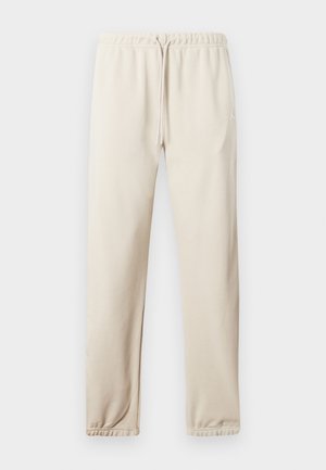 Harmaat beiget jogging-housut, joissa on joustava vyötärö, säädettävä nyöri ja hihansuut. Sivussa pieni logo. Pehmeä kangas.