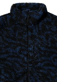 Giacca in pile morbido di colore blu scuro e nero con colletto alto, chiusura a zip frontale e motivo testurizzato. Presenta una tasca con zip sul petto.