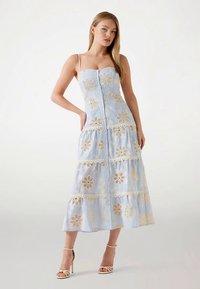 Lichtblauwe midi-jurk met bloemrijke kanten applicaties en knoopsluiting. A-lijn ontwerp, dunne bandjes en gelaagde ruches aan de zoom.