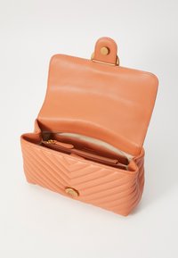 Quiltad orange läderhandväska med magnetknapp, med en beige inredning och flera fack för organisering.