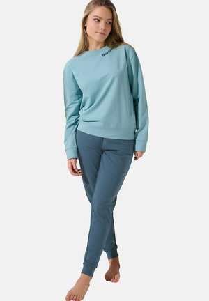Lichtblauwe sweatshirt met een ronde hals en lange mouwen, gecombineerd met donkerblauwe slim-fit broek. Zacht materiaal met minimale details.