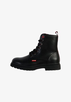 Boots en cuir noir à la cheville avec des accents rouges, bout rond, design à six œillets avec lacets, semelle en caoutchouc texturé et une languette au talon.