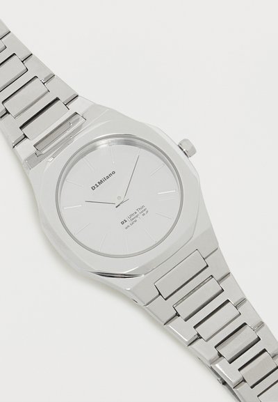 Ασημένιο μεταλλικό ρολόι χειρός με μινιμαλιστικό λευκό καντράν, λεπτά ασημένια δείκτες και σήμανση D1 Milano στο καντράν και στο λουράκι.