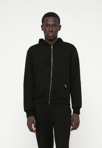 Black zip-up hoodie made of soft cotton. Features a front pocket, ribbed cuffs, and hem. Smooth texture with a minimalistic design.