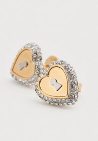 Σκουλαρίκια σε σχήμα καρδιάς με χρυσή απόχρωση και σχέδιο κλειδαρότρυπας, περιβαλλόμενα από διαφανείς στρας. Διαθέτουν λαμπερό φινίρισμα και κομψό περίγραμμα.