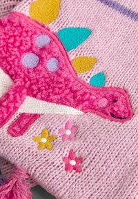 Lyserød strikket stof med en fluffy lyserød dinosaur, der har farverige pigge og broderede blomster i gul, lyserød og hvid.