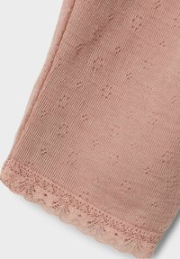 Un textile tricoté rose clair avec un motif texturé de petites fleurs et une bordure en dentelle au bord inférieur. Matériau doux avec de fins détails.