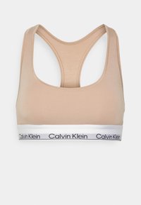 Sportivo beige con design a racerback e fascia bianca. La fascia presenta un testo nero che recita "Calvin Klein". Materiale morbido con una texture liscia.