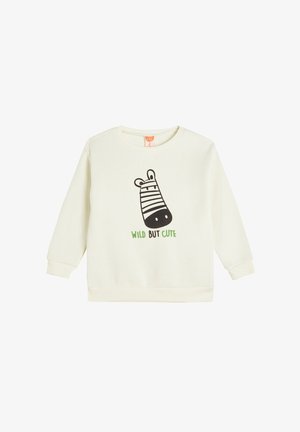 Crème kleurig sweatshirt met lange mouwen, voorzien van een zwart zebra graphic en groene tekst met "WILD BUT CUTE" aan de voorkant.