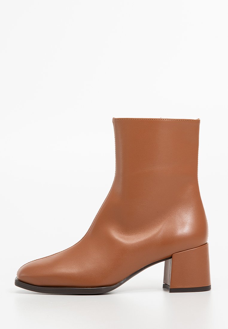 Bruine leren enkelboot met een vierkante neus en chunky hak. Glad textuur en minimalistisch ontwerp, met een lichte glans.