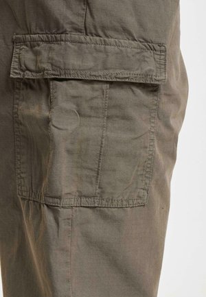 Cargo pants in olive green fabric with a textured surface. Features a large side pocket and reinforced stitching along seams.
