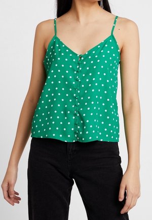 Camisola verde a pois con spalline sottili, chiusura a bottoni e vestibilità ampia. Il tessuto ha una texture liscia ed un aspetto luminoso e vivace.