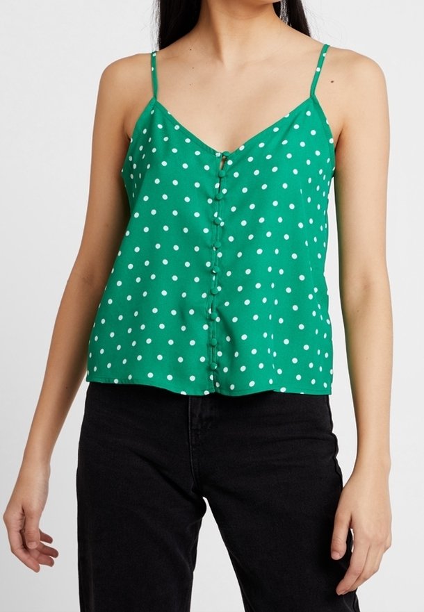 Camisola verde a pois con spalline sottili, chiusura a bottoni e vestibilità ampia. Il tessuto ha una texture liscia ed un aspetto luminoso e vivace.