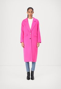 Rosa ullblandad kappa med notched krage, enda knappstängning, två framfickor och långa ärmar, i kombination med ljusblå jeans och svarta stövlar.