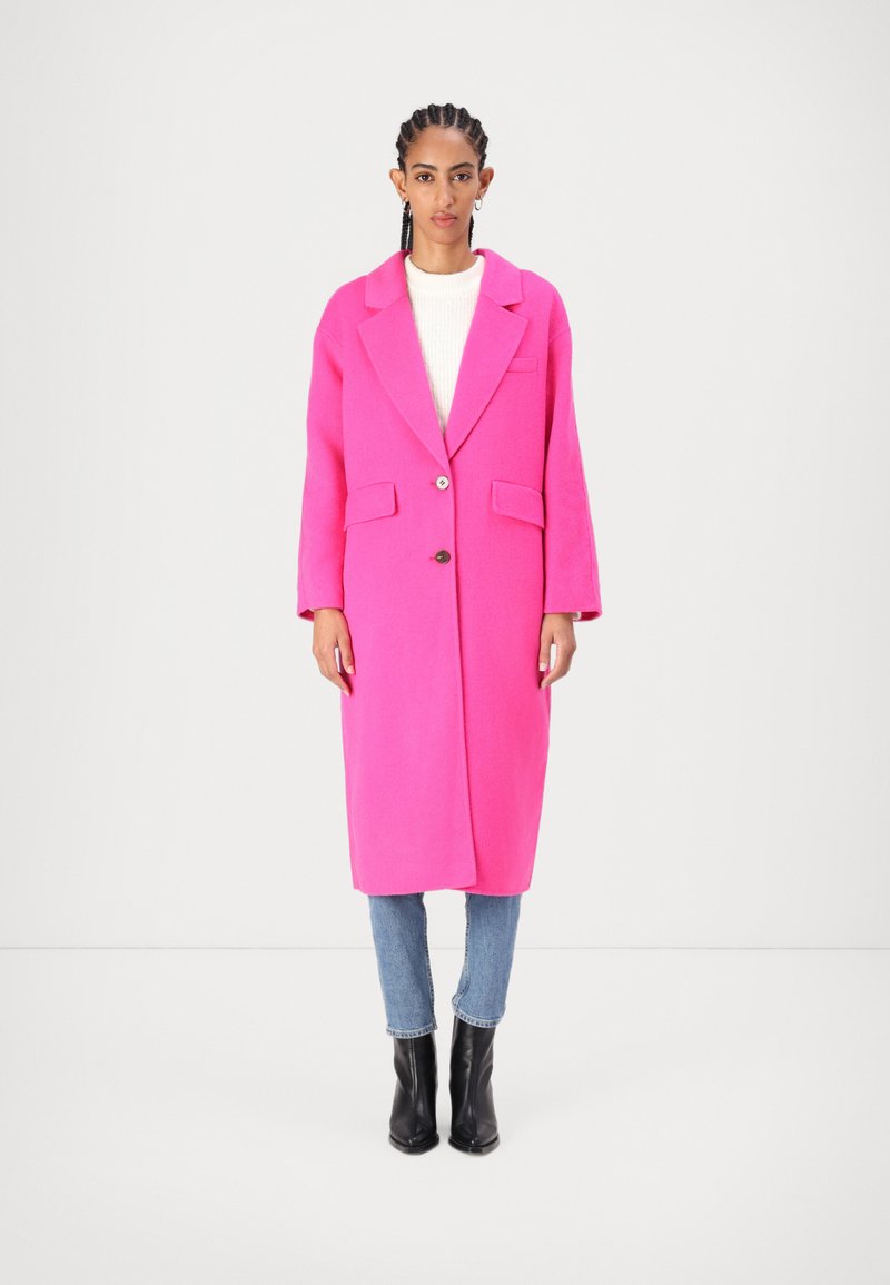 Rosa ullblandad kappa med notched krage, enda knappstängning, två framfickor och långa ärmar, i kombination med ljusblå jeans och svarta stövlar.