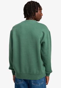 Grüner Baumwollpullover mit einem einfachen, lockeren Schnitt. Verfügt über einen runden Ausschnitt und gerippte Bündchen, mit einer glatten Textur und ohne sichtbare Muster.