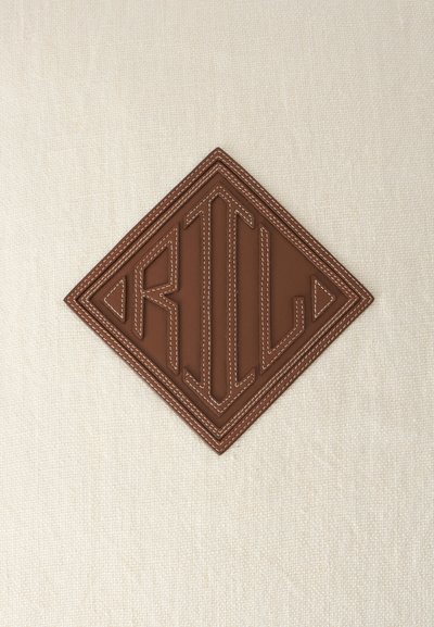 Patch en cuir marron avec le mot "RILL" cousu sur un tissu beige en forme de losange avec des détails en fil blanc.