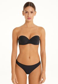 Černý bikiny top bez ramínek s tvarovanými košíčky a odpovídajícími spodními díly, s hladkým povrchem a minimalistickým designem. Bez dalších ozdob.