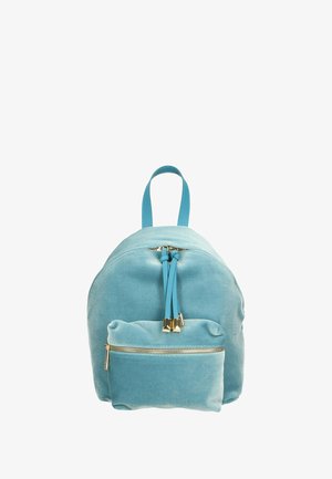 Lichtblauwe canvas rugzak met een afgeronde vorm, voorzien van een ritsvak aan de voorkant, dubbele ritsen en twee schouderbanden. Accenten van goudkleurig beslag.