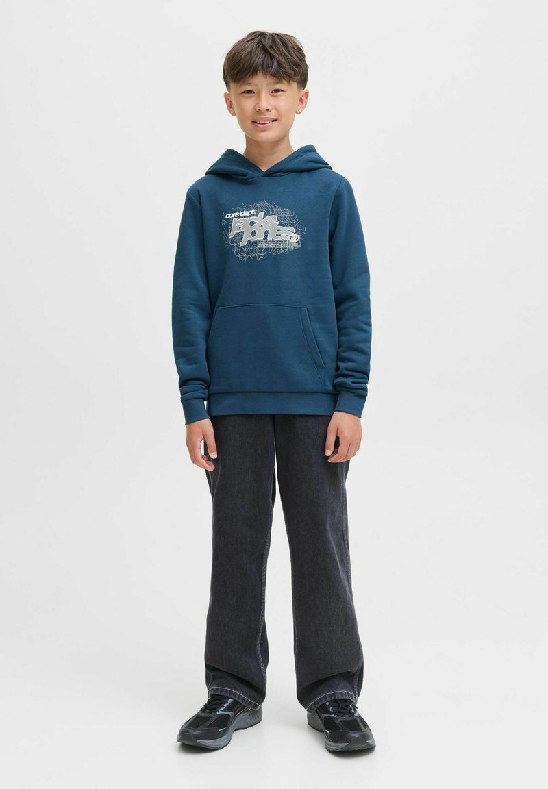 Felpa blu navy con design grafico, tasca a marsupio frontale e polsini a costine. Abbinata a pantaloni grigi scuri e scarpe nere.