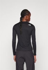 Maglietta atletica nera a maniche lunghe con un design aderente e scollatura arrotondata. Presenta il logo The North Face sulla parte superiore della schiena.