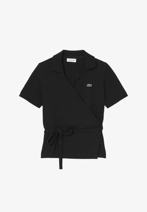 Polo nera a maniche corte con scollo a incrocio, cintura laterale annodata e piccolo logo di coccodrillo verde sul petto.