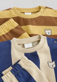 Two striped baby outfits with elastic waistbands, snap buttons on shoulders, and small bear face embroidery on the chest.