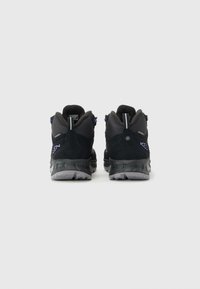 Pair of black and gray hiking shoes with purple accents, sturdy soles, and pull tabs, shown from the back on a white background.