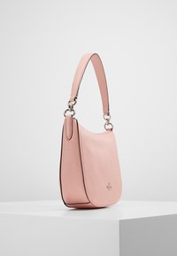Sac à main en cuir rose avec une finition texturée, une bandoulière unique et des ferrures argentées. Présente une forme incurvée et un design minimaliste.