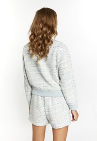 Lichtblauwe tweed sweatshirt met geribde manchetten en zoom, gecombineerd met bijpassende shorts. De textuurstof heeft een geweven patroon.