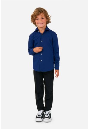 Camicia a maniche lunghe blu navy con colletto appuntito, abbinata a pantaloni neri e sneakers bianco e nere. Design liscio e su misura.