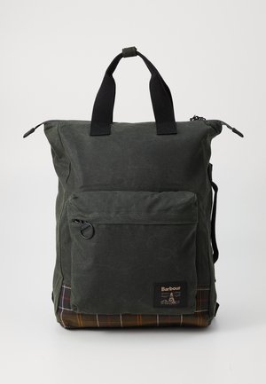 Dark green waxed cotton backpack with black handles, front zip pocket, and brown plaid bottom panel, branded with Barbour logo patch.