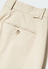 Pantaloni beige in tessuto liscio, con tasca posteriore chiusa da bottone e dettagli di cuciture sottili. Etichetta decorativa in vita.