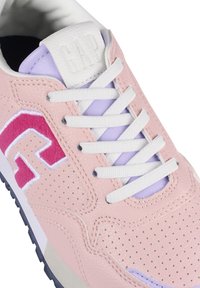 Helle rosa Sneaker aus strukturiertem Leder, mit weißen Schnürsenkeln und einem lila Akzent nahe der Zunge. Enthält ein pinkes Logo und perforierte Details.